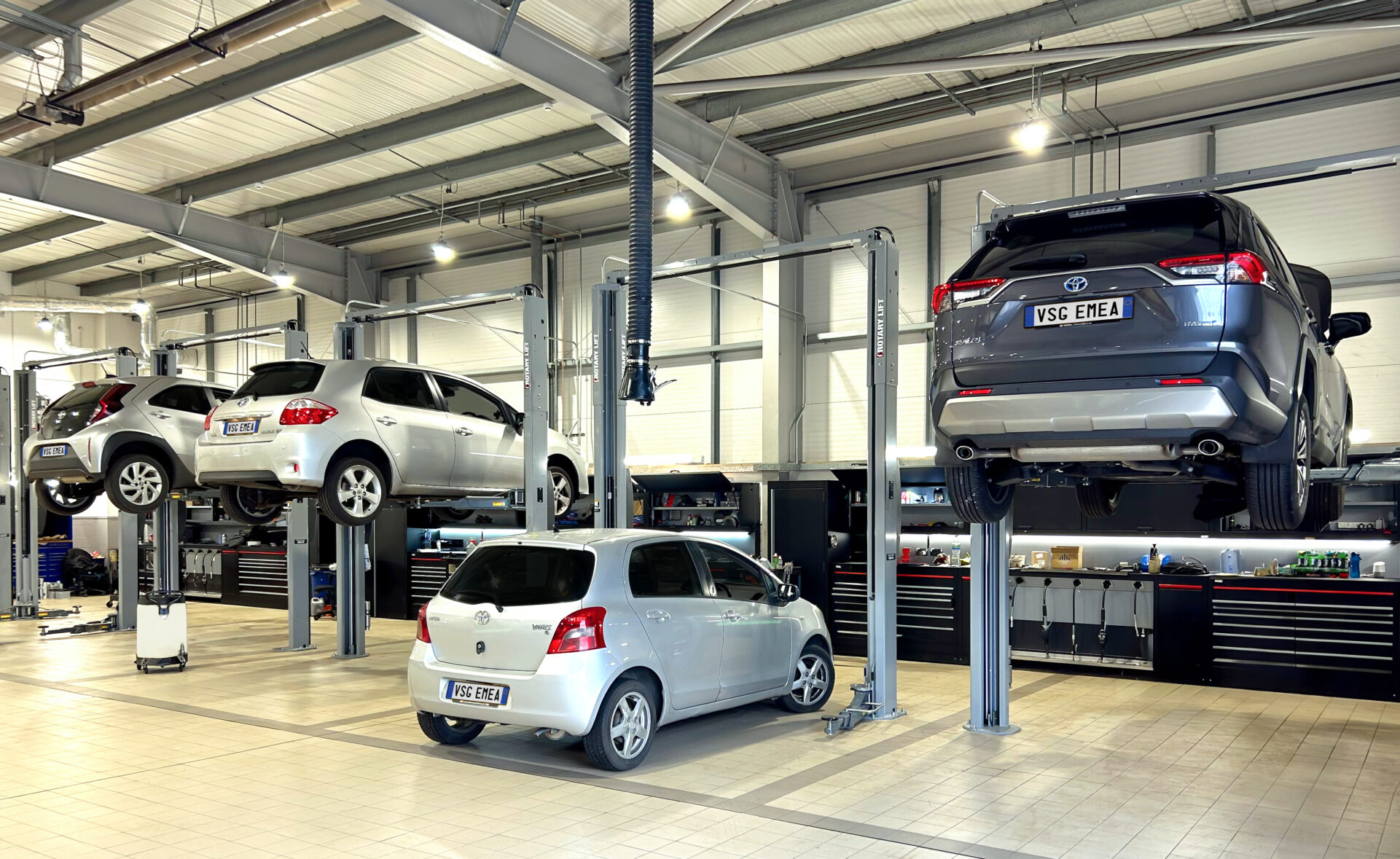 Four cars are lifted by Rotary car lifts at a dealership