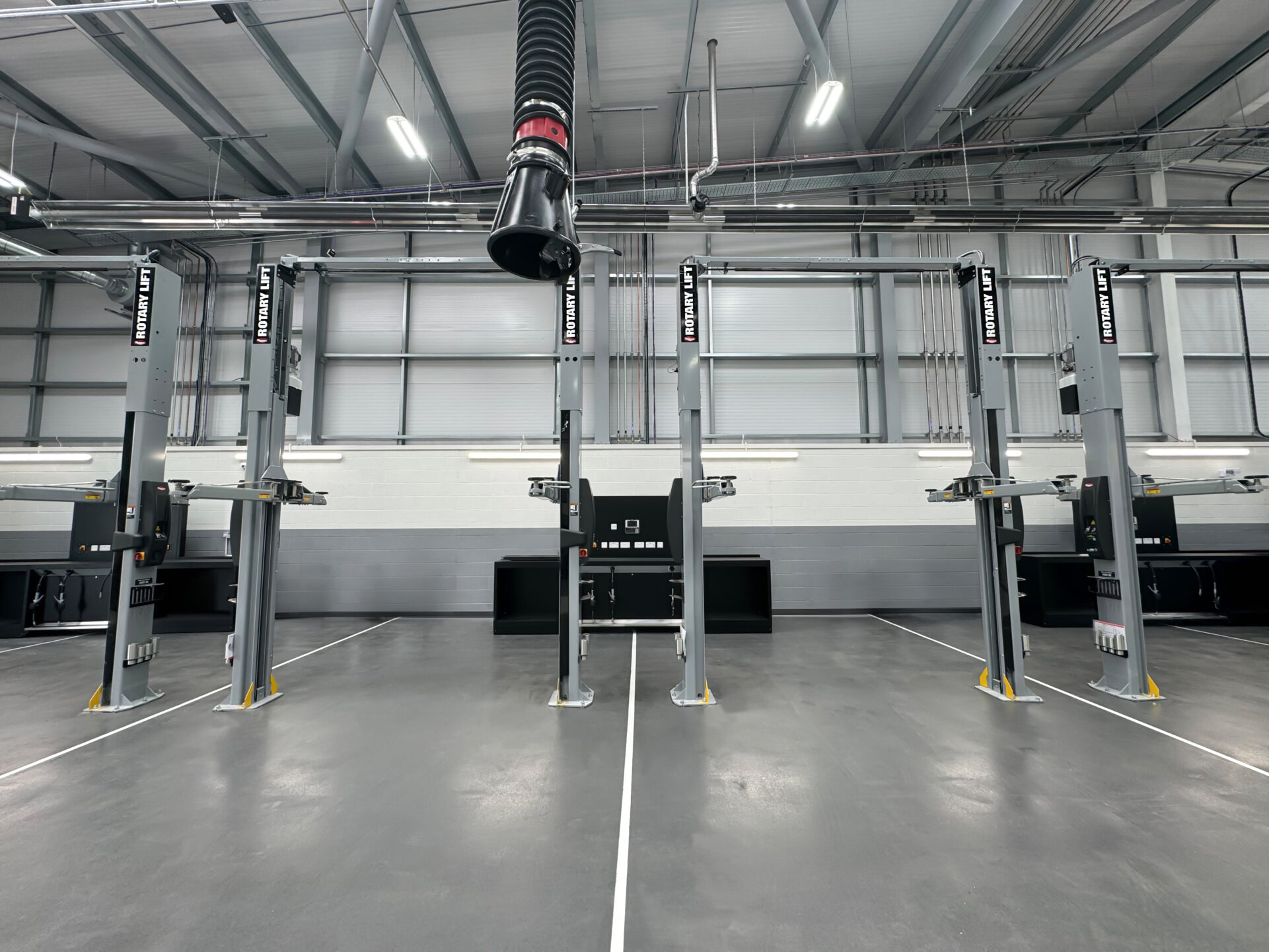 Frontal shot of four gray Rotary two-post lifts in a repair shop